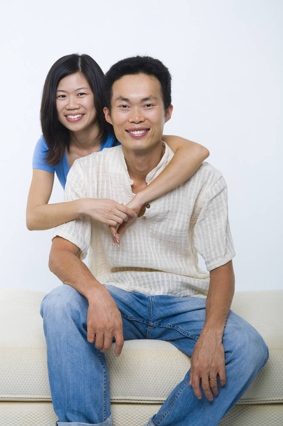 Young Asian couple sitting on sofa with smiling face, on white background. - 写真・画像