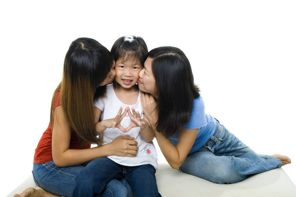 Asian family kissing little girl face on white background. Sisterly love. - Fotoğraf, Görsel