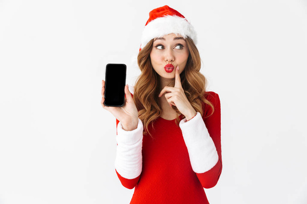 Picture of a beautiful emotional woman in christmas costume showing display of mobile phone. - Фото, зображення