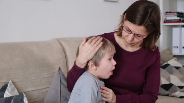 Cute little boy is coughing, sitting with his mother in a living room - Video