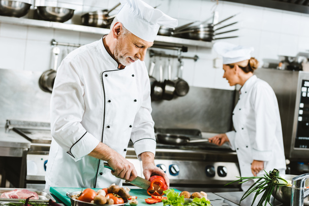 enfoque selectivo de chefs masculinos y femeninos en uniforme preparando comida en la cocina del restaurante
 - Foto, imagen