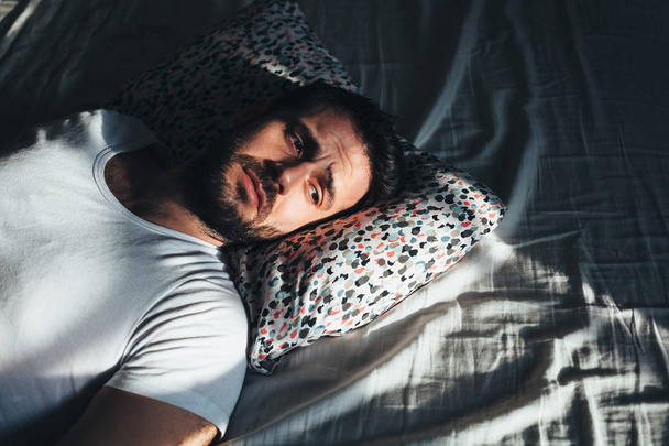 Nuori masentunut mies itkee sängyssä
 - Valokuva, kuva
