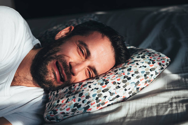 Молодой депрессивный мужчина плачет в постели
 - Фото, изображение
