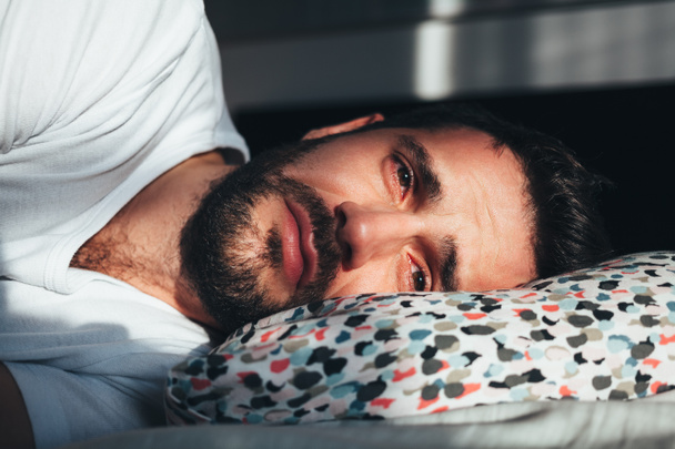 Young depressed man crying in bed - Φωτογραφία, εικόνα