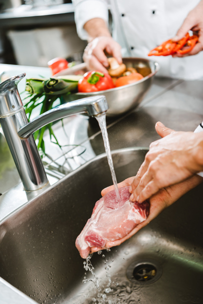 cropped view of female chef washing raw meat in restaurant kitchen - Foto, afbeelding