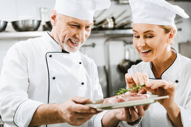chef masculino feliz presentación de plato de carne a colega en la cocina del restaurante
 - Foto, Imagen