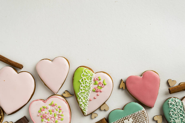 Painted gingerbread with cinnamon and hearts on a white background. Bakery products. Gingerbread in the shape of a heart. Place for text. Gingerbread pattern Background. - Zdjęcie, obraz