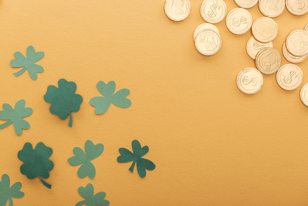 top view of golden coins with dollar signs, shamrocks and copy space isolated on orange, st patrick day concept - Фото, изображение