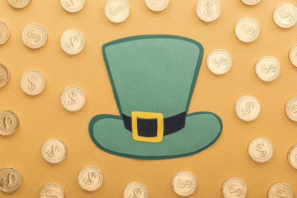top view of golden coins with dollar signs and green paper hat isolated on orange, st patrick day concept - Foto, Imagem