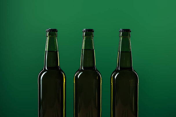 row of beer bottles isolated on green, st patrick day concept - 写真・画像