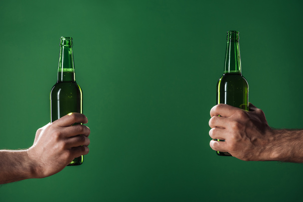 cropped view of men holding beer bottles isolated on green with copy space, st patrick day concept - Fotó, kép