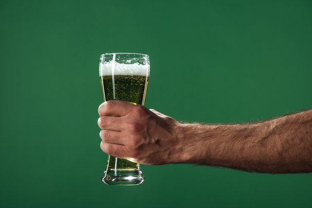cropped view of man holding glasses of beer with foam isolated on green, st patrick day concept - Valokuva, kuva