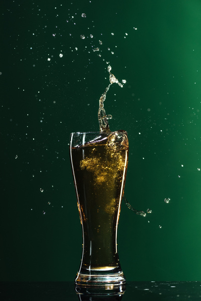 studené pivo s tryskající izolované na zelené, st patrick day koncept - Fotografie, Obrázek