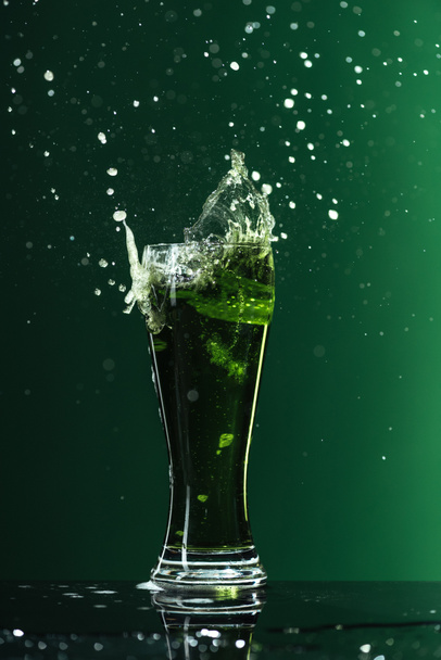 glas bier met spatten geïsoleerd op groen, st patrick dag concept - Foto, afbeelding