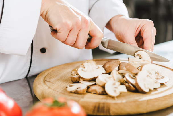 partial view of female chef cutting mushrooms in restaurant kitchen - Фото, изображение
