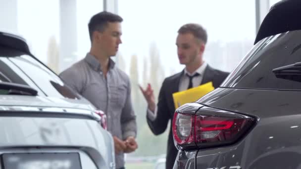 Selektywny fokus na samochód, mężczyzna klienta rozmowa do dealera auto na tle - Materiał filmowy, wideo