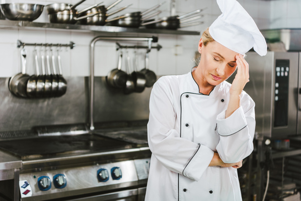 bella cuoca stanca in uniforme con mal di testa in cucina ristorante con spazio copia
 - Foto, immagini