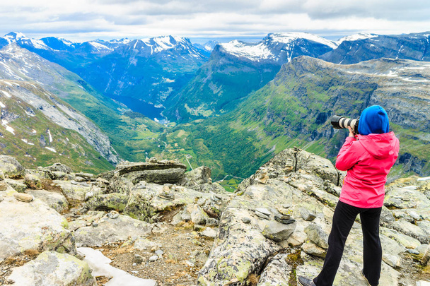 Tourism vacation and travel. Female tourist taking photo with camera, enjoying Geiranger fjord and mountains landscape from Dalsnibba Plateau viewpoint, Norway Scandinavia. - Fotoğraf, Görsel