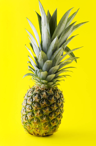 Verticale foto. Concept van reizen, vakantie. Verse exotische ananas op helder geel papier - Foto, afbeelding