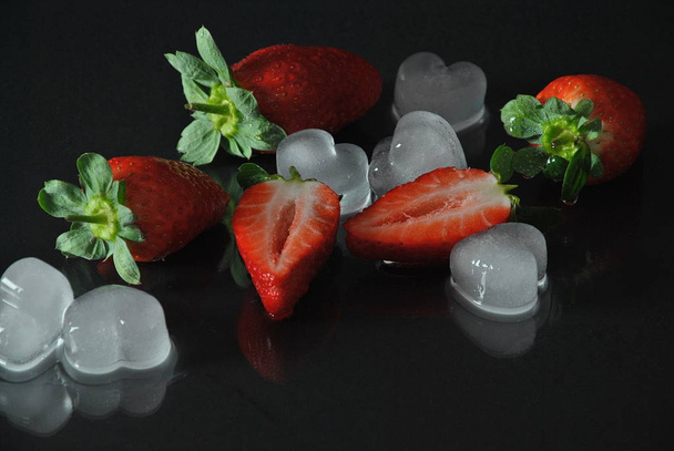 Fresh strawberries and ice on black with reflection - Photo, image