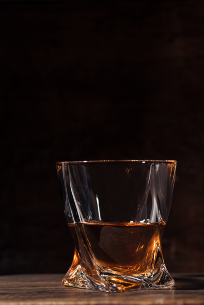 close-up view of whiskey in glass on wooden table on black  - Photo, Image