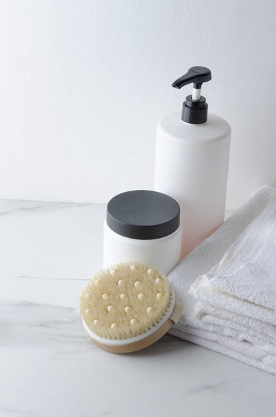 Bouteilles de baume pour les cheveux, shampooing et pile de serviettes blanches sur étagère en marbre blanc.
 - Photo, image