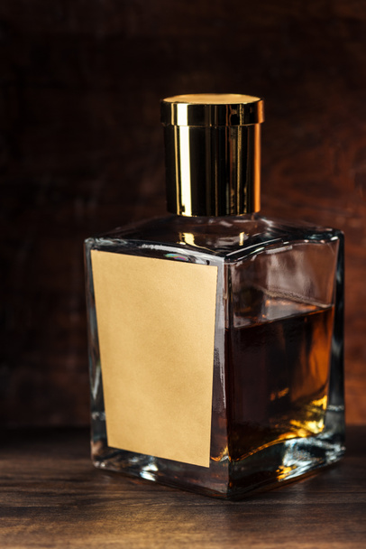 Nahaufnahme einer Luxus-Cognacflasche mit leerem Etikett auf Holztisch  - Foto, Bild