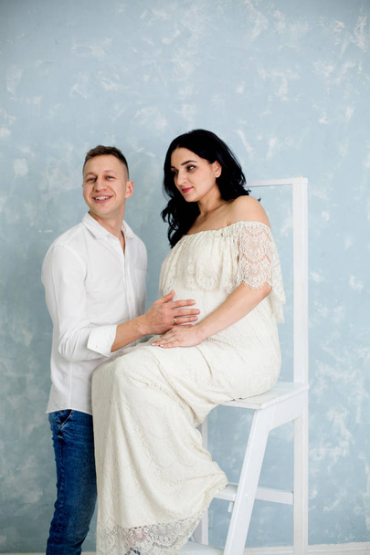 椅子の上の白いドレスに妊娠中の女性と幸せなカップル - 写真・画像