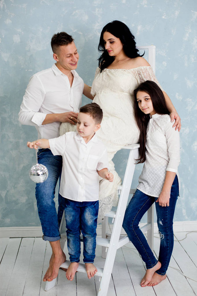 glückliche Familie mit schwangerer Frau und Kindern posiert im Studio - Foto, Bild
