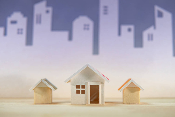 Ingatlan vagy ingatlan beruházás. Home design koncepció. Faház modellek a város városkép háttér az asztalon. Lakóépület fejlesztése - Fotó, kép