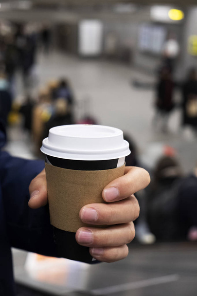 primer plano de un joven tomando una taza de café para llevar en una estación de metro o una estación de tren
 - Foto, imagen
