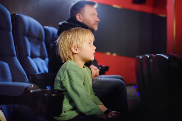 Cute little boy with his father watching cartoon movie in the cinema. Leisure/entertainment for family with kids. - Photo, image