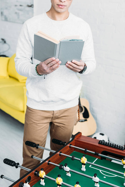 partial view of man reading book while standing by football table - Photo, Image