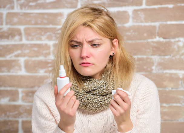 Allergy concept. Home treatment. Effective nasal spray. Runny nose and other symptoms of cold. Nasal drops plastic bottle. Nasal spray runny nose remedy. Girl sick person hold nasal drops and tissue - Foto, Imagen