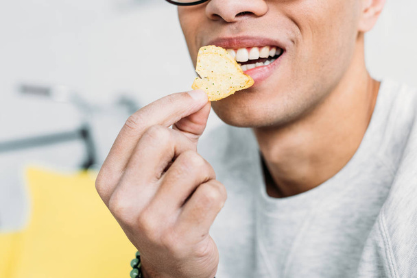 обрезанный вид человека в белой толстовке, поедающего чипсы
 - Фото, изображение