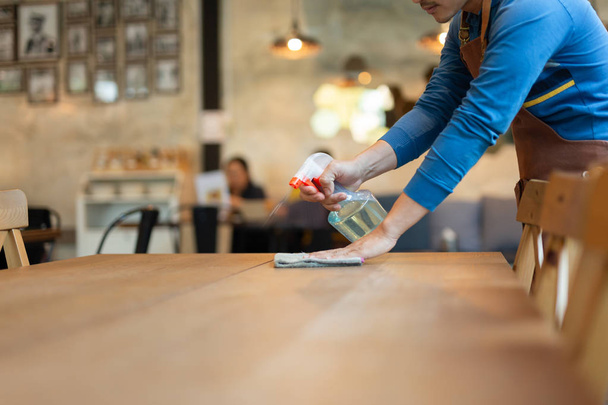 Cameriere pulire il tavolo con spray disinfettante sul tavolo nel ristorante
 - Foto, immagini