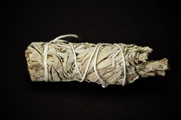 A bundle of dried white sage used for smudging, used by native americans for cleansing and shamanic ceremonies on black background - Foto, afbeelding