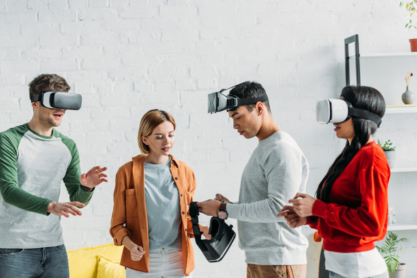 multi-etnisch vrienden zetten van virtuele realiteit headsets  - Foto, afbeelding