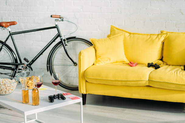 salón con cómodo sofá amarillo y mesa con bebidas y aperitivos
 - Foto, Imagen