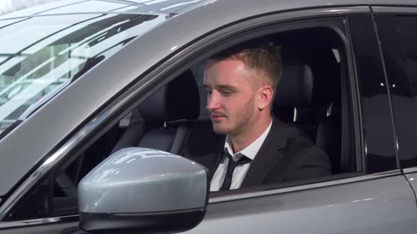 Vrolijke zakenman holding autosleutels zitten in een nieuwe auto bij de dealer - Video