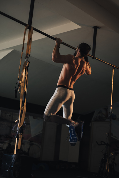 Shirtless athlete man with beard doing pull ups on the bar in the gym - Foto, afbeelding