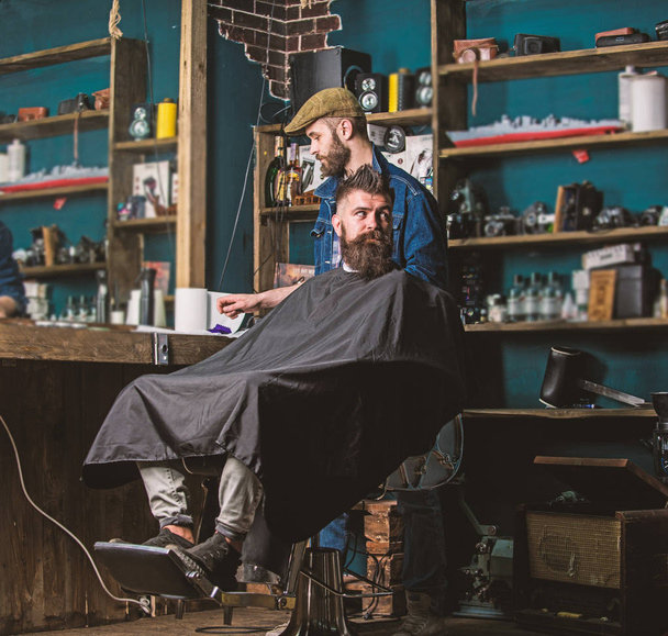 Barber with hair clipper in hand finished trimming. Hipster client getting haircut. Barber with hair clipper works on hairstyle for bearded man barbershop background. Haircut process concept - Φωτογραφία, εικόνα