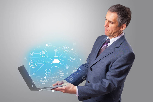 Άνθρωπος που κρατά το laptop με το cloud με βάση σύστημα έννοια - Φωτογραφία, εικόνα