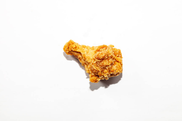 Primer plano de un ala de pollo apetitosa grasa frita en un pan de harina marrón sobre un fondo blanco, alimentos grasos poco saludables que causan una enfermedad con colesterol elevado
. - Foto, imagen