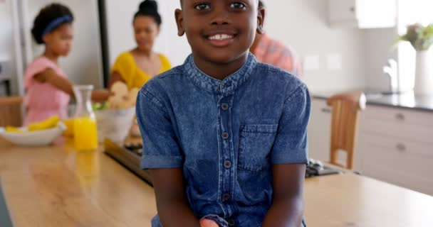 Front view of happy black boy looking at camera. Black family eating food in the background 4k - Séquence, vidéo