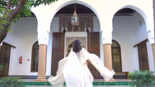 Το όμορφο Μαρόκου κορίτσι κουνώντας το φως λευκό μανδύα στο γραφικό Dar Si είπε Ριάντ στο Μαρακές, κατά το ηλιοβασίλεμα - Πλάνα, βίντεο
