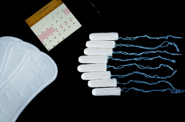 Концепція менструального періоду. Захист жіночої гігієни. Бавовняні тампони на чорному тлі. Вид зверху, плоский ліжко
 - Фото, зображення