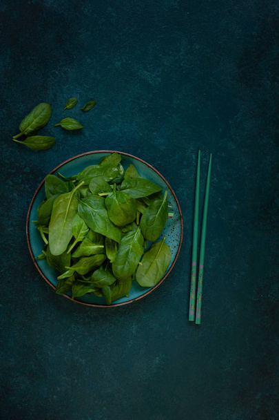 Fresh green baby spinach leaves with Chopsticks on green background - Photo, Image