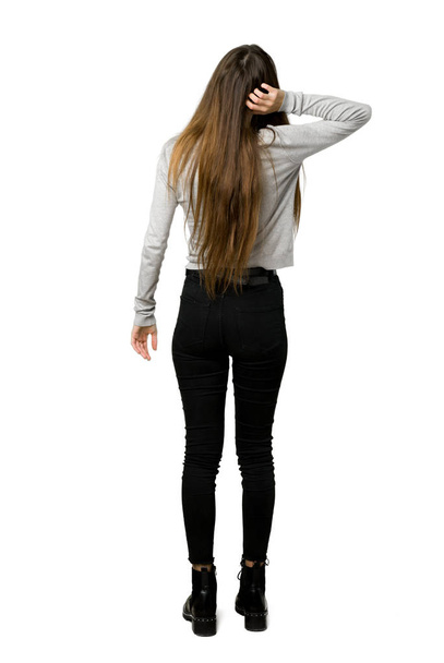 Full-length shot of young girl on back position looking back while scratching head on isolated white background - Foto, Bild
