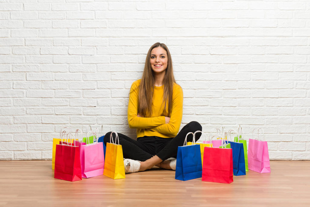 Jong meisje met veel shopping tassen houden de armen gekruist in frontale positie - Foto, afbeelding
